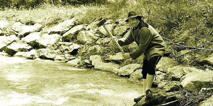Ein Arbeiter steht mit seinem Werkzeug bei einem Fluß